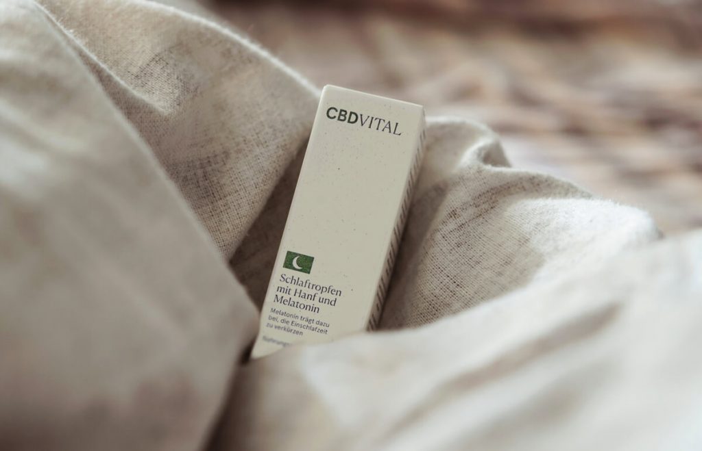 CBD Vital olej na kvalitný spánok s obsahom melatonínu - krabička s olejom položená v prikrývkach