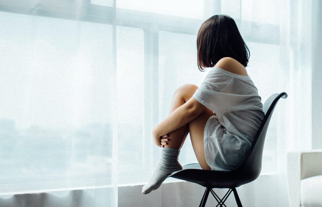 Ilustračný obrázok - psychické problémy: mladá žena sediaca pri okne