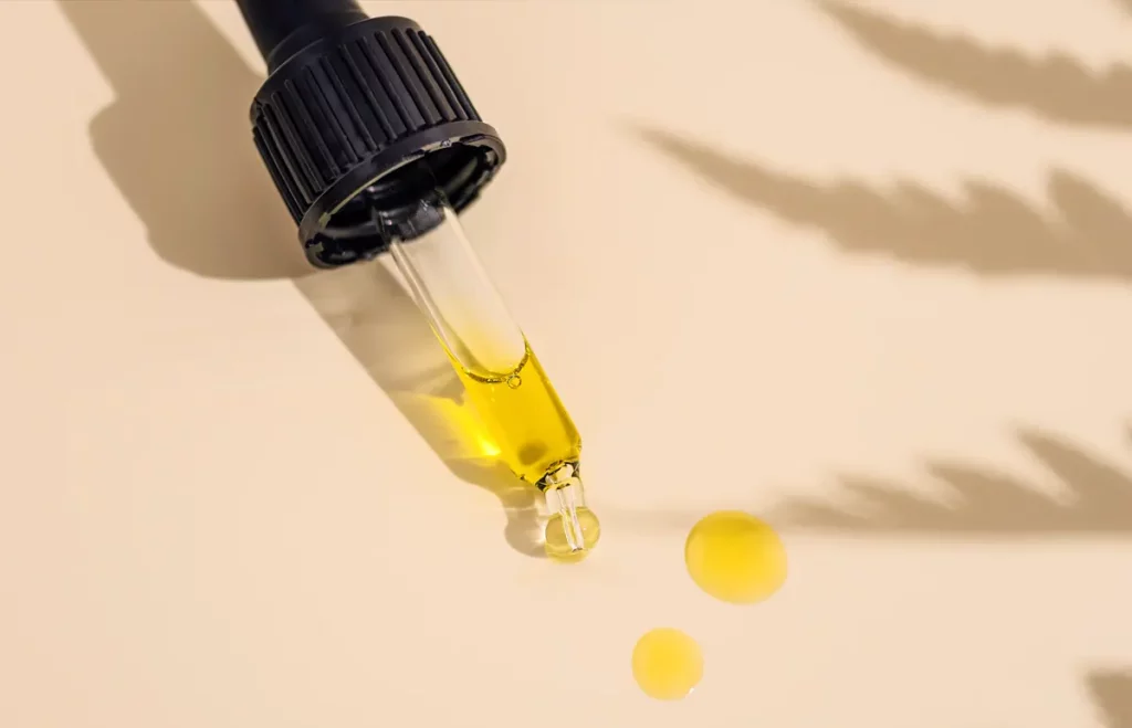 CBD olej - pipeta s natiahnutým cbd olejom zlatej farby